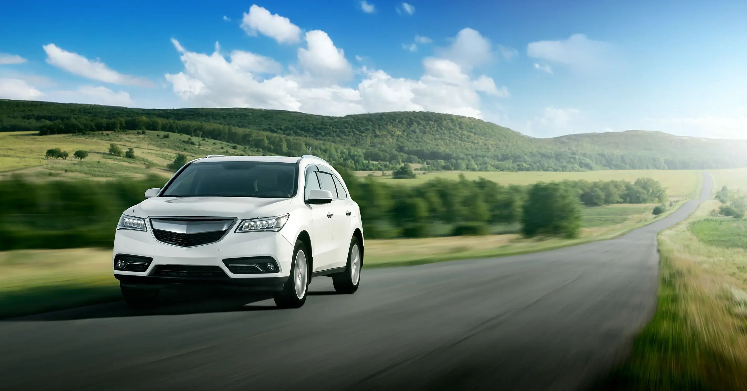 White SUV driving on a highway along green scenery.